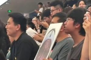詹姆斯中國行成都活動現(xiàn)場 一球迷拿著詹姆斯經(jīng)典哭臉照坐在場邊